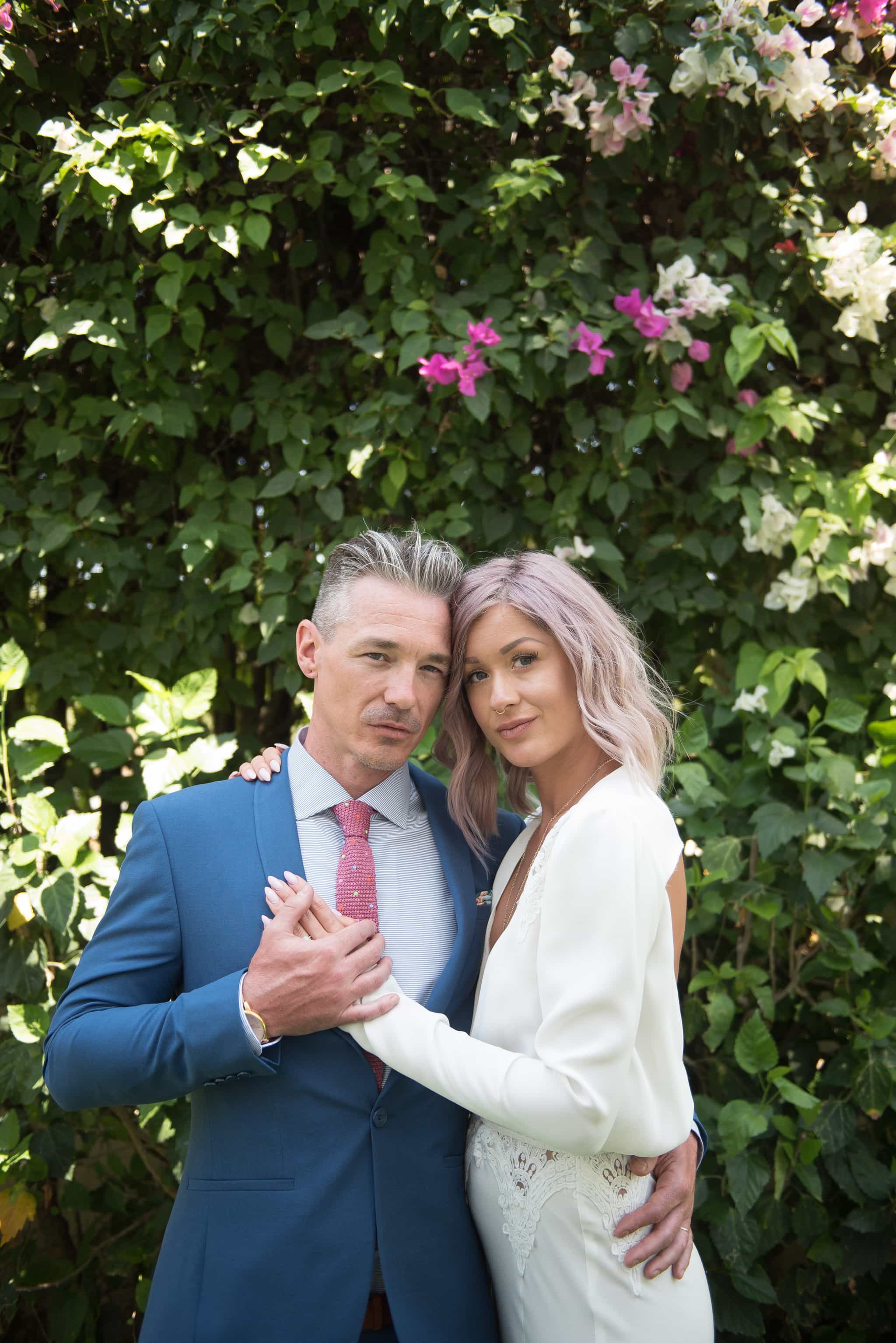 Bride and groom against wall of greenery