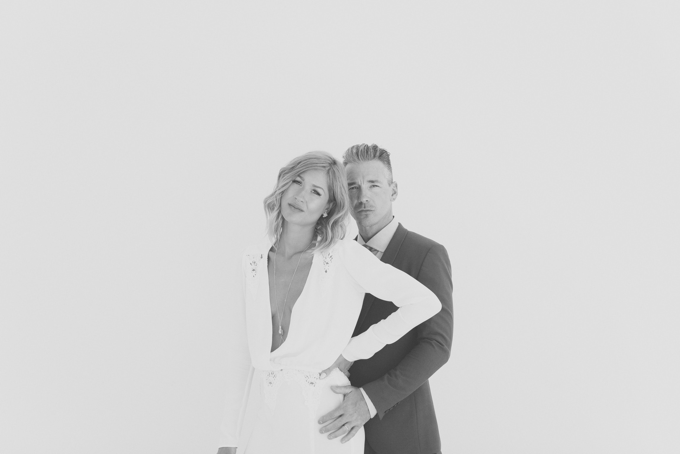 Iconic bride and groom in front of white wall 