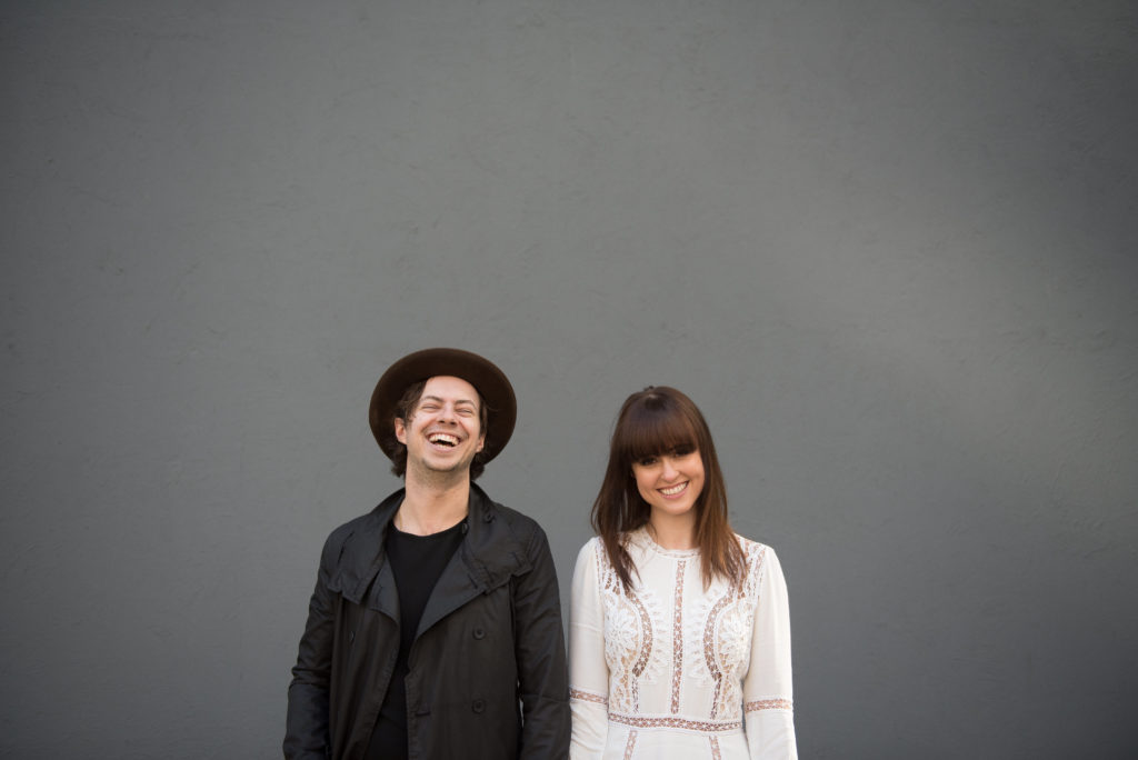 Beautiful couple stands in front of blank grey wall