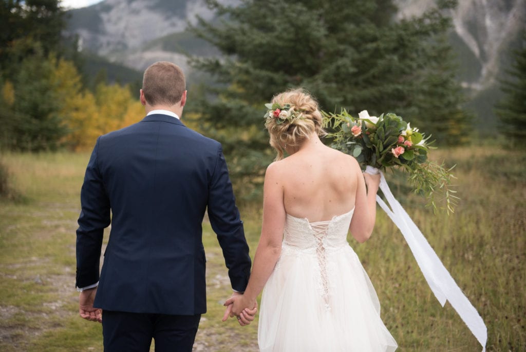 a year in review bride and groom walk towards the mountains as a small breeze takes her bouquet