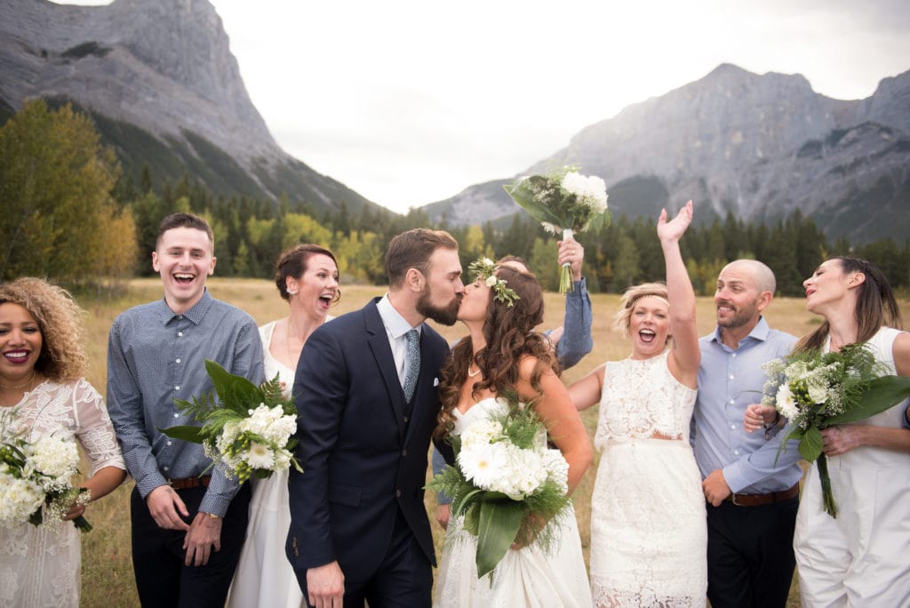a year in review bridal party throw hands up behind bride and groom kissing