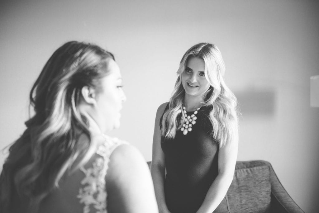 a year in review bridesmaid smiles at bride as she gets her dress done up 