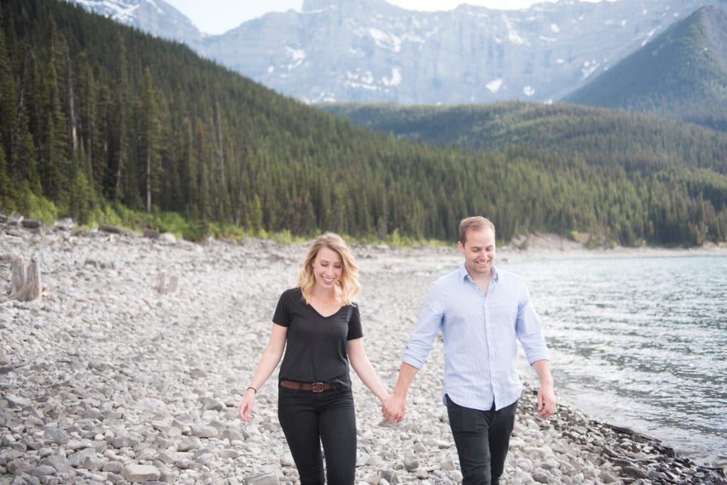 a year in review couple holds hands and runs along lake in Alberta Rockies