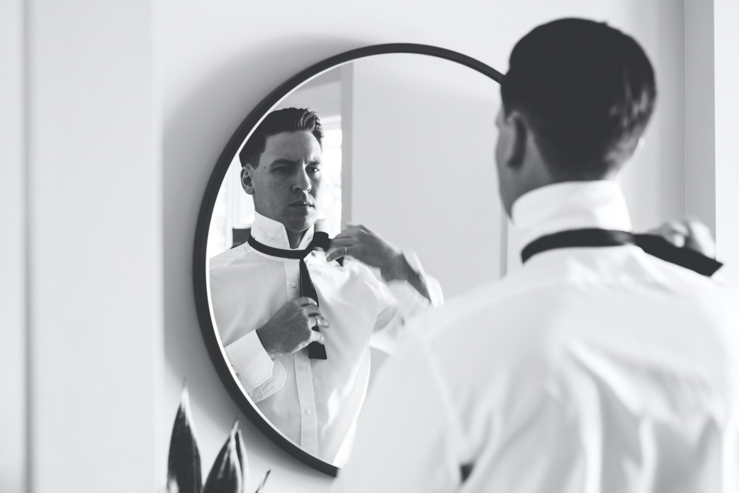 Black and White image of groom getting ready in mirror reflection