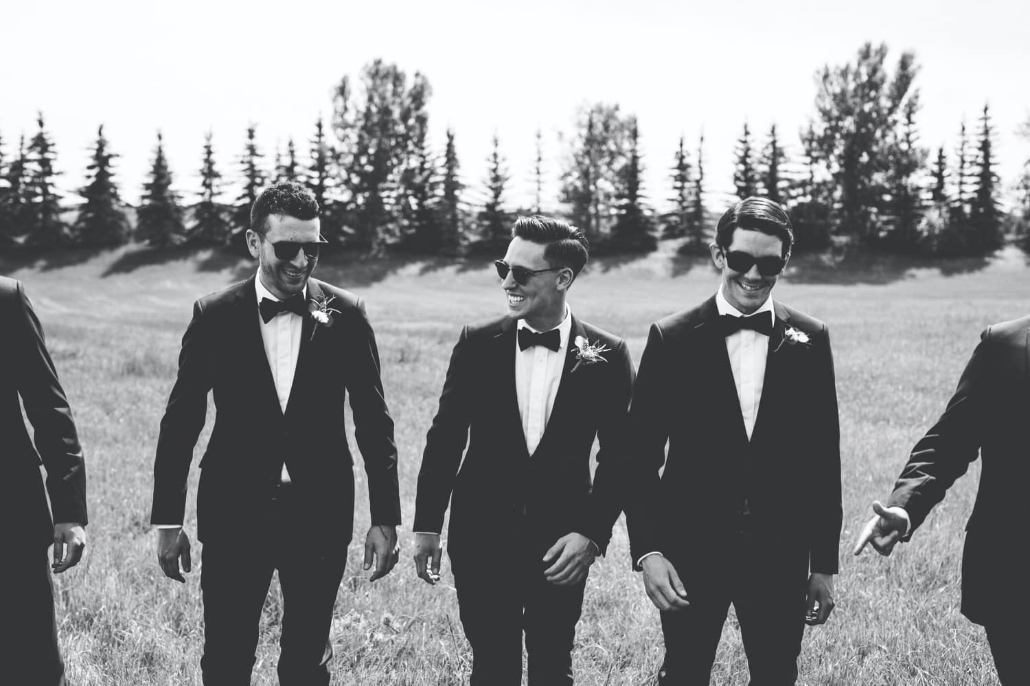 Dapper groomsmen walking through field