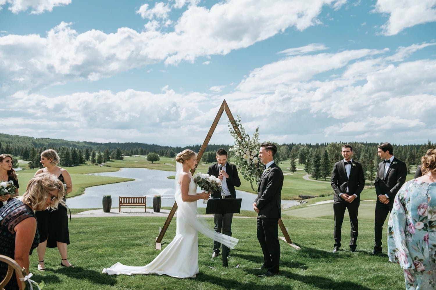 Bride and groom with triangle arbour in front of lake