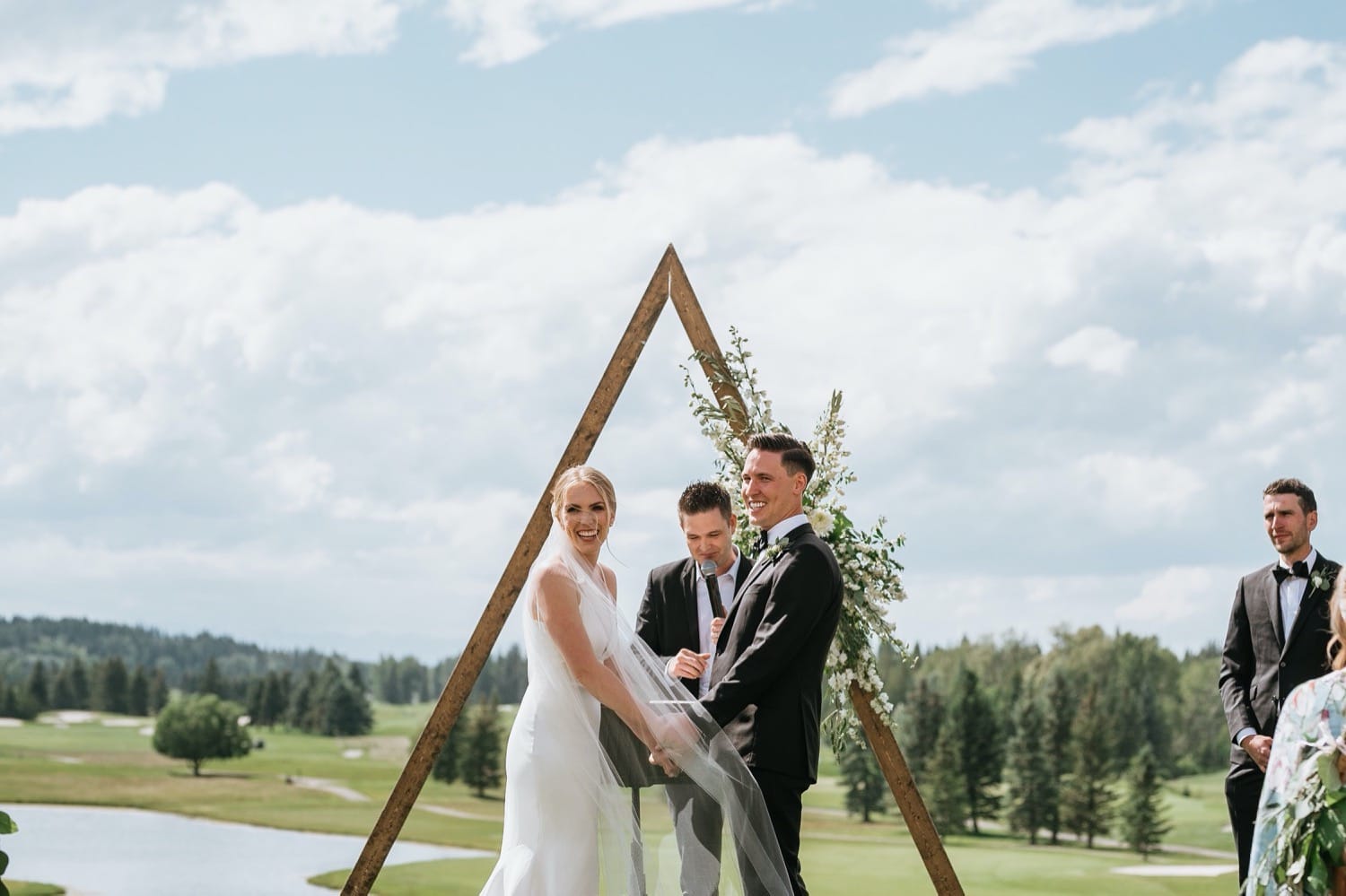 Bride and groom standing in front of arbour